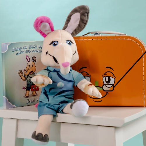 Amley op een kruk met EHBO-boekje Kleine snijwond, Woko de Koffer en herbruikbare pleisters en snijwondbandje – een speelse introductie in eerste hulp voor kinderen.